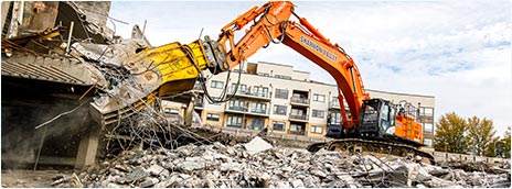 Процесс демонтажа здания экскаватором